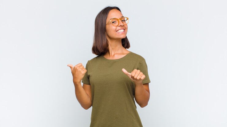 Photo latin woman smiling cheerfully and casually pointing to copy space on the side, feeling happy and satisfied