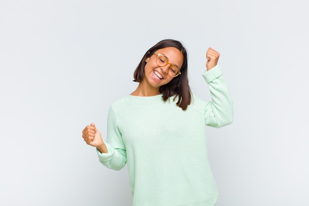 Latin woman smiling, feeling carefree, relaxed and happy, dancing and listening to music, having fun at a party