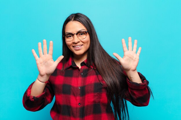 Latin woman smiling and looking friendly, showing number ten or tenth with hand forward, counting down