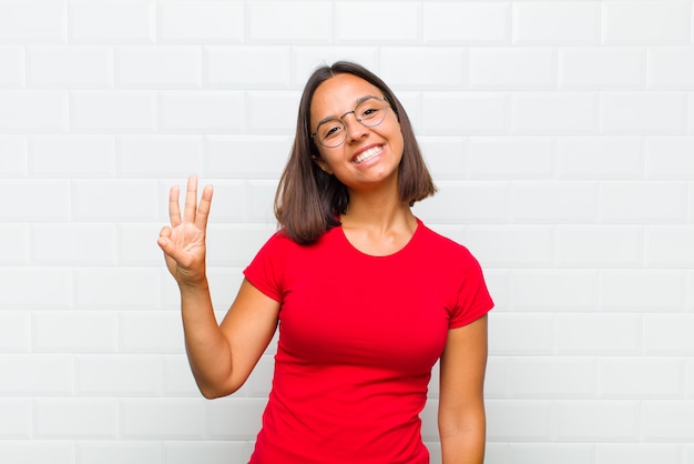 Latin woman smiling and looking friendly, showing number two or second with hand forward, counting down