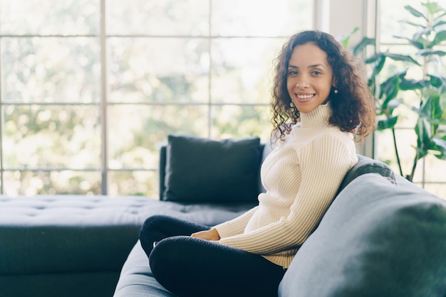 Latin woman smiling and sitting on sofa