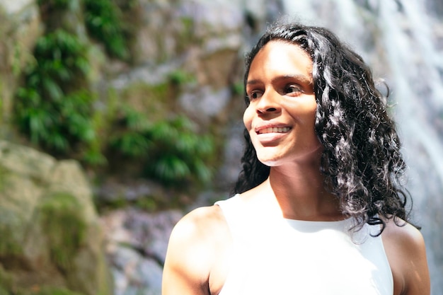 Latin woman standing by a waterfall. Vacation and Tourism Concept