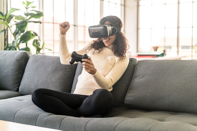 Latin woman using a virtual reality headset on sofa at home