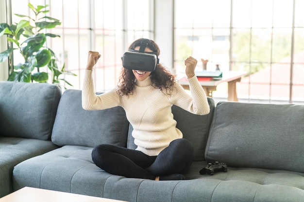 Latin woman using a virtual reality headset on sofa at home