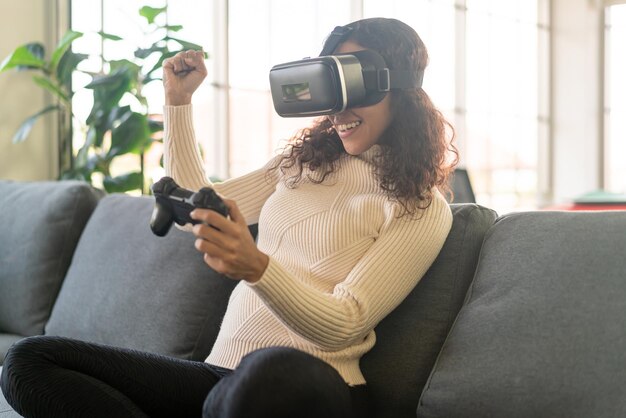 Latin woman using a virtual reality headset on sofa at home