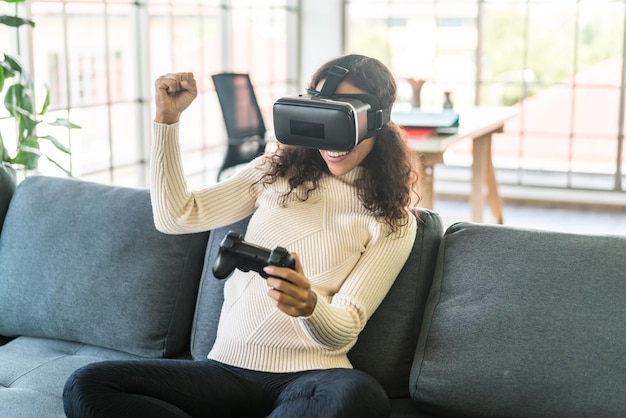 Latin woman using a virtual reality headset on sofa