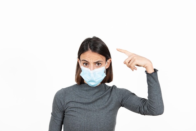 Latin woman wearing a surgical mask making crazy sign with her hand