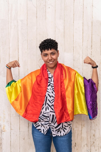 Latin woman with arms outstretched holding rainbow flag