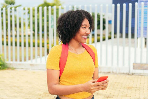 Latin Woman with backpack and mobile phone at park