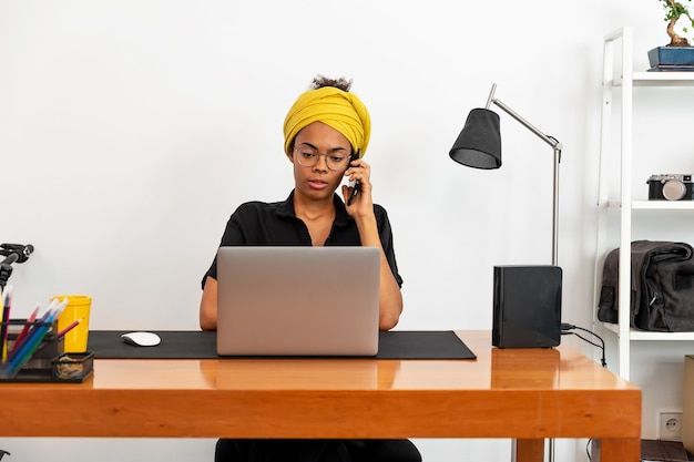 Latin woman working at home office with laptop and documents