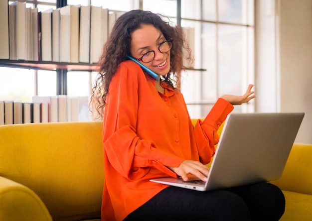 latin woman working with laptop on sofa at home