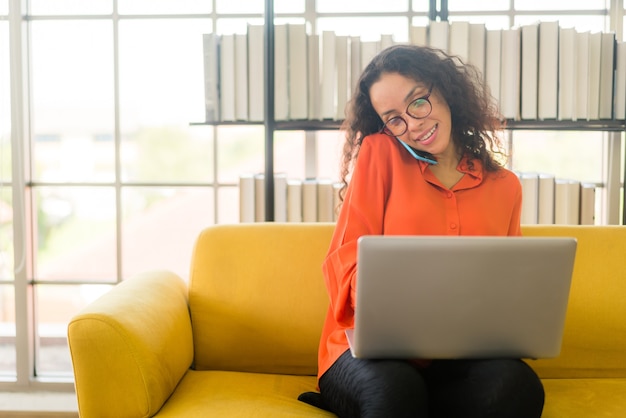 Latin woman working with laptop on sofa at home