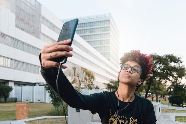 Латинская молодая колумбийская брюнетка с афро на улице делает селфи со своим мобильным телефоном