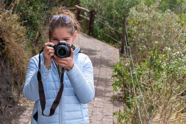 Foto giovane donna latina escursionista che scatta una foto con una macchina fotografica professionale turista spensierato sorridente