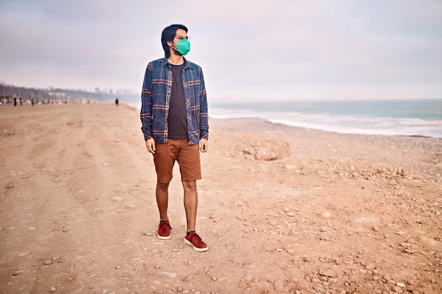 Latin young man poses walking on the sand during a beautiful sunset