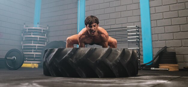 Giovane latino che lavora con un pneumatico del trattore in una palestra crossfit