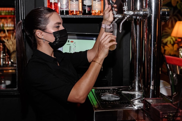 Латинская молодая женщина подает бокал пива на барной стойке. работа официантка профессия