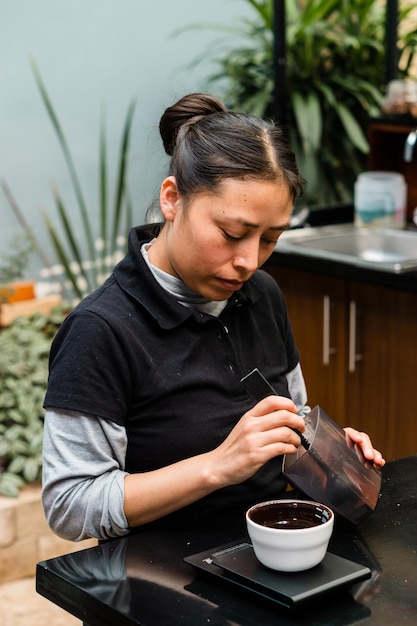 Latina female employee of a coffee shop preparing coffee.