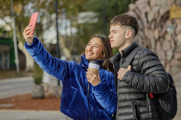 Latina girl and Caucasian boy taking a selfie with their mobile phone