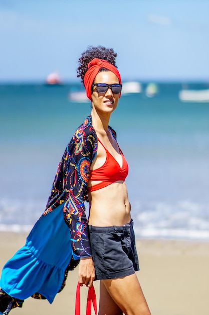 Latina schoonheid slanke vrouw poseren en wandelen met kleurrijke zomerkleding op een tropisch winderig strand