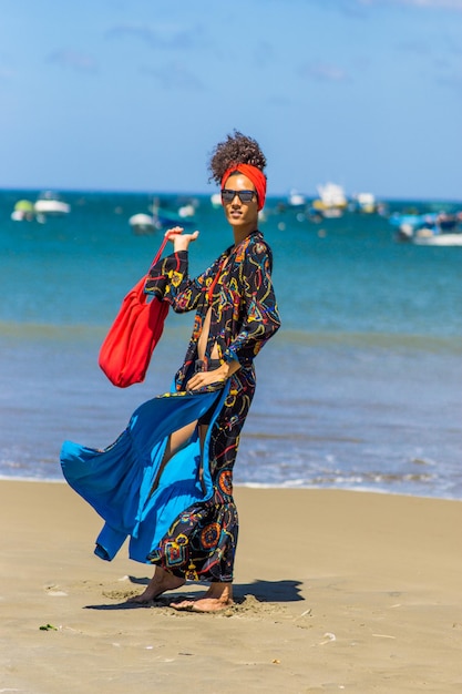 Latina schoonheid slanke vrouw poseren en wandelen met kleurrijke zomerkleding op een tropisch winderig strand