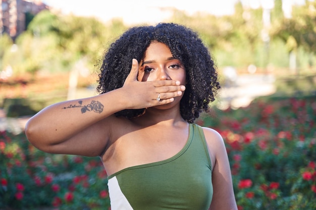 Latina teen with curly hair covering her mouth with her hand