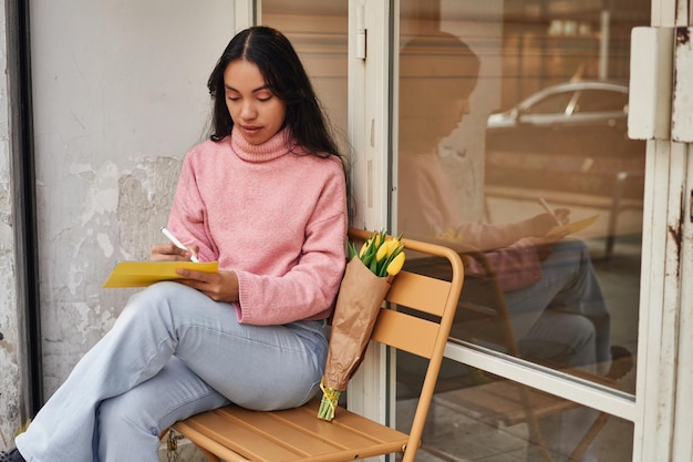 Latina vrouw schrijft liefdesbrief met gele tulpen