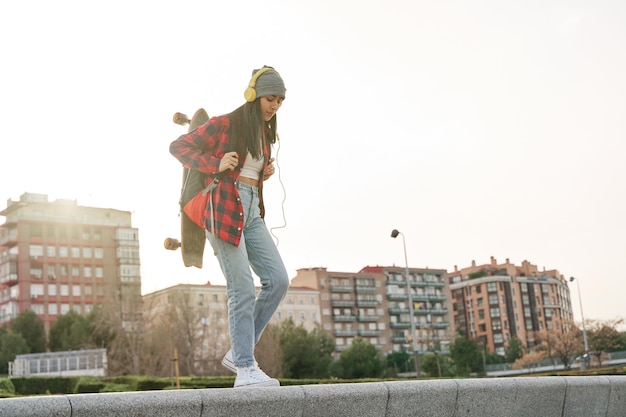 latina wandelen in de stad met een rugzak en een skateboard