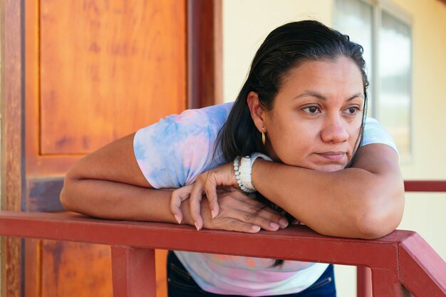 Latina woman outside her home in thought