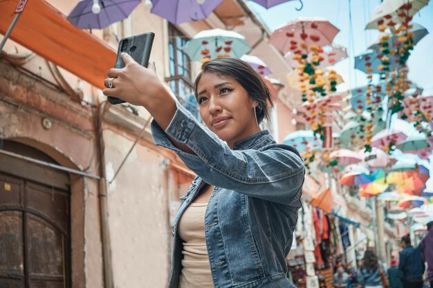 Photo latina woman on vacation taking a selfie with her cell phone in the historic streets of bolivia