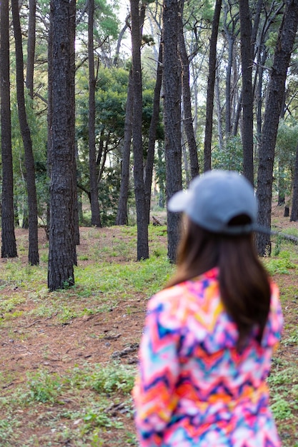 latina woman with cap and multicolored sporty campero out of focus in a vertical autumn forest