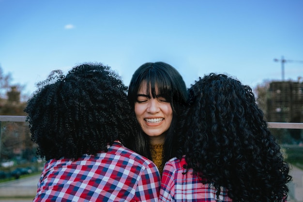 目を閉じたラティーナの女性は、友人の肩に寄りかかって微笑み、幸せで外にいる