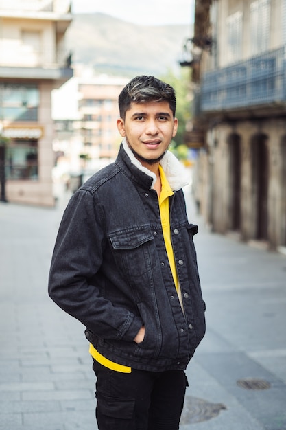 Latino man op straat met handen in jaszak camera kijken
