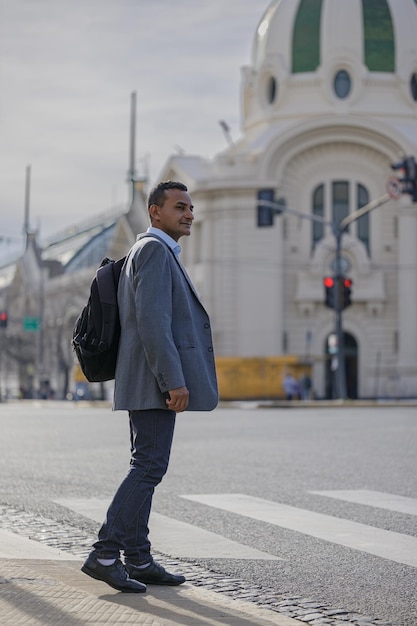 Photo latino man in a suit and backpack crossing the street in a city