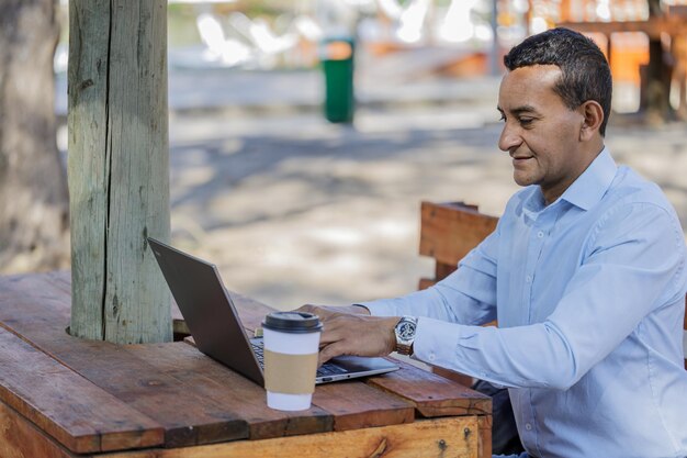 Latino man using a laptop outdoors