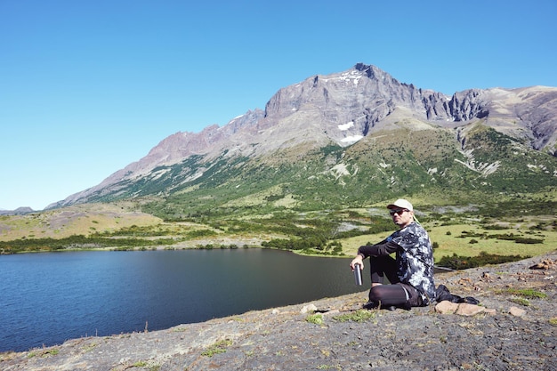 Latino mature hiker sitting on the rocks above the lagoon contemplating the beauty