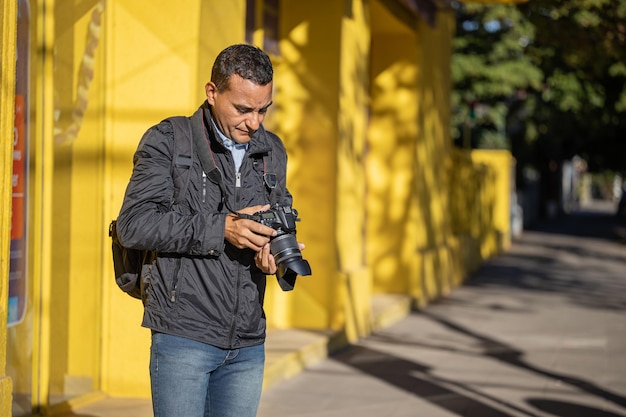 Latino photographer checking a photograph on his camera with copy space