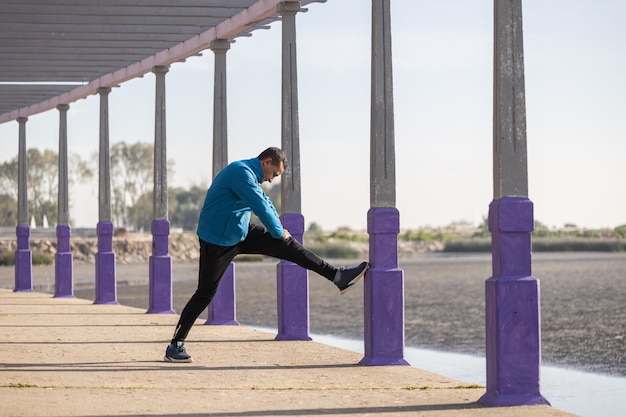 Latino runner stretching in a pergola in a public park