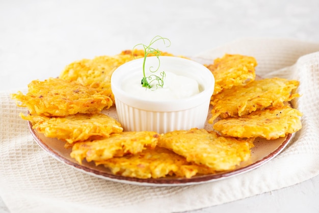 Latkes or Levivot potato pancakes draniki with sour cream and green on a light table Hanukkah food