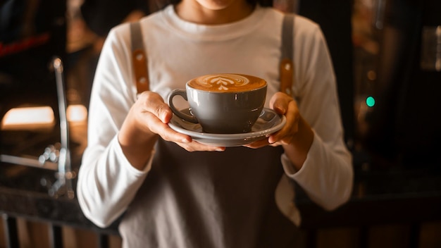 Latte art in barista hand ready to drink in modern coffee shop