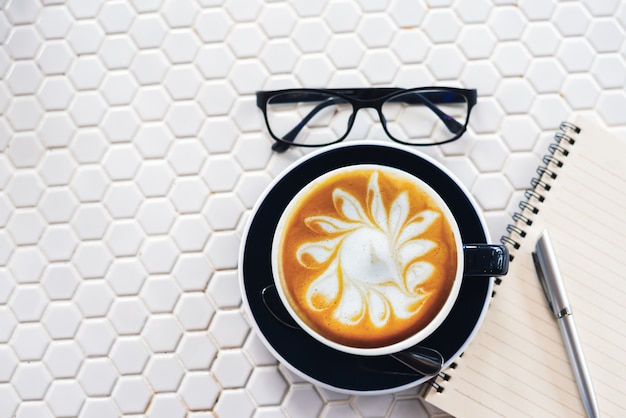 Latte art cup of coffee on white table