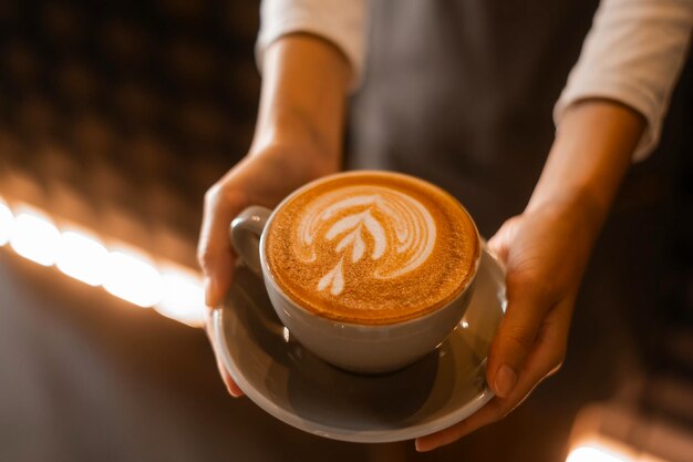 Latte art in barista hand klaar om te drinken in moderne coffeeshop