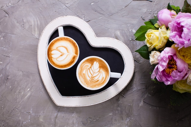Latte art in twee kopjes cappuccino op het hartvormige dienblad. Fijne morgen Valentijnsdag paar
