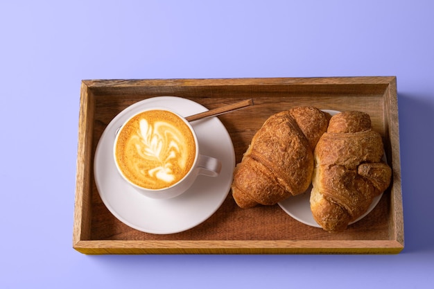 Latte art koffie, croissants op trendy Very Peri kleur - kleur van het jaar 2022 achtergrond.