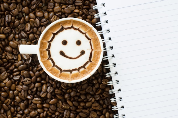 Latte art and notebook on coffee bean background