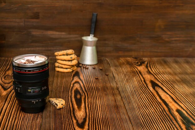 Latte coffee cacao with milk, marshmallow in thermo cup, zoom lens mug, cookies on wooden background, hot beverage in cold weather.