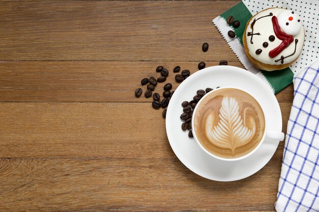 Latte coffee or cappuccino coffee and christmas donut on wooden table