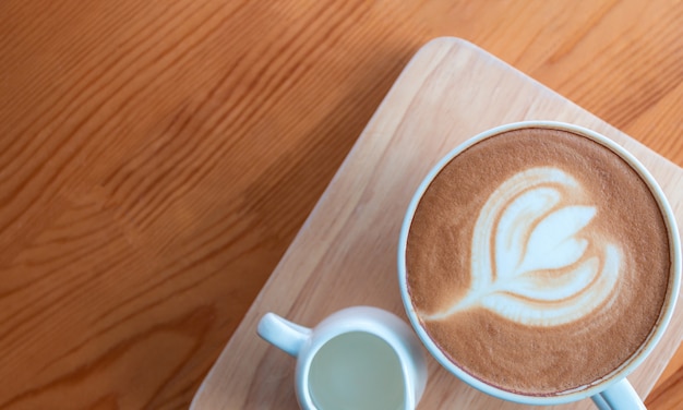 Tazza di caffè del latte con arte del latte sulla tavola di legno in caffetteria.