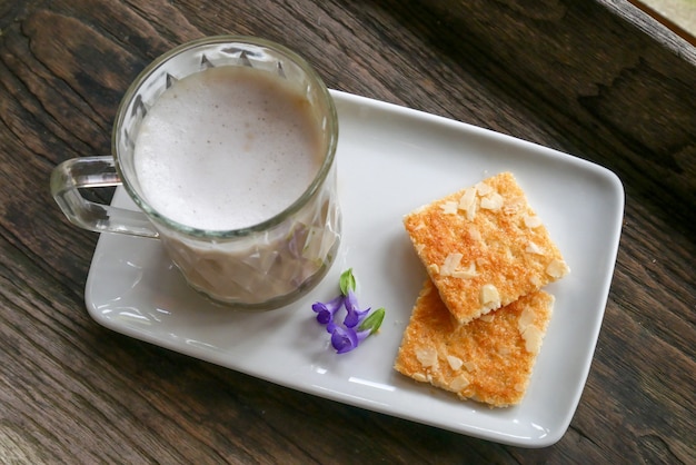 Foto latte caffè in una tazza sul pavimento di legno con biscotti al mattino.