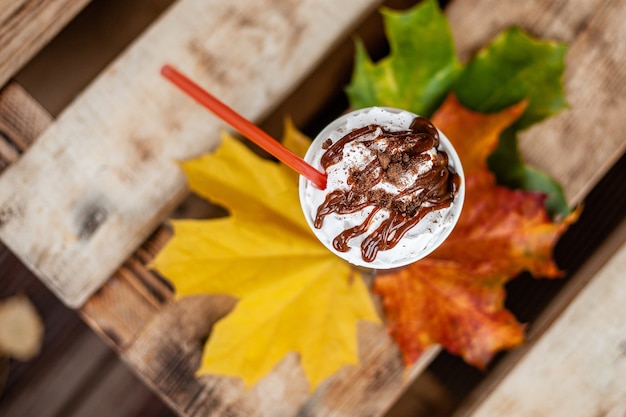 秋の葉にストローでラテコーヒー